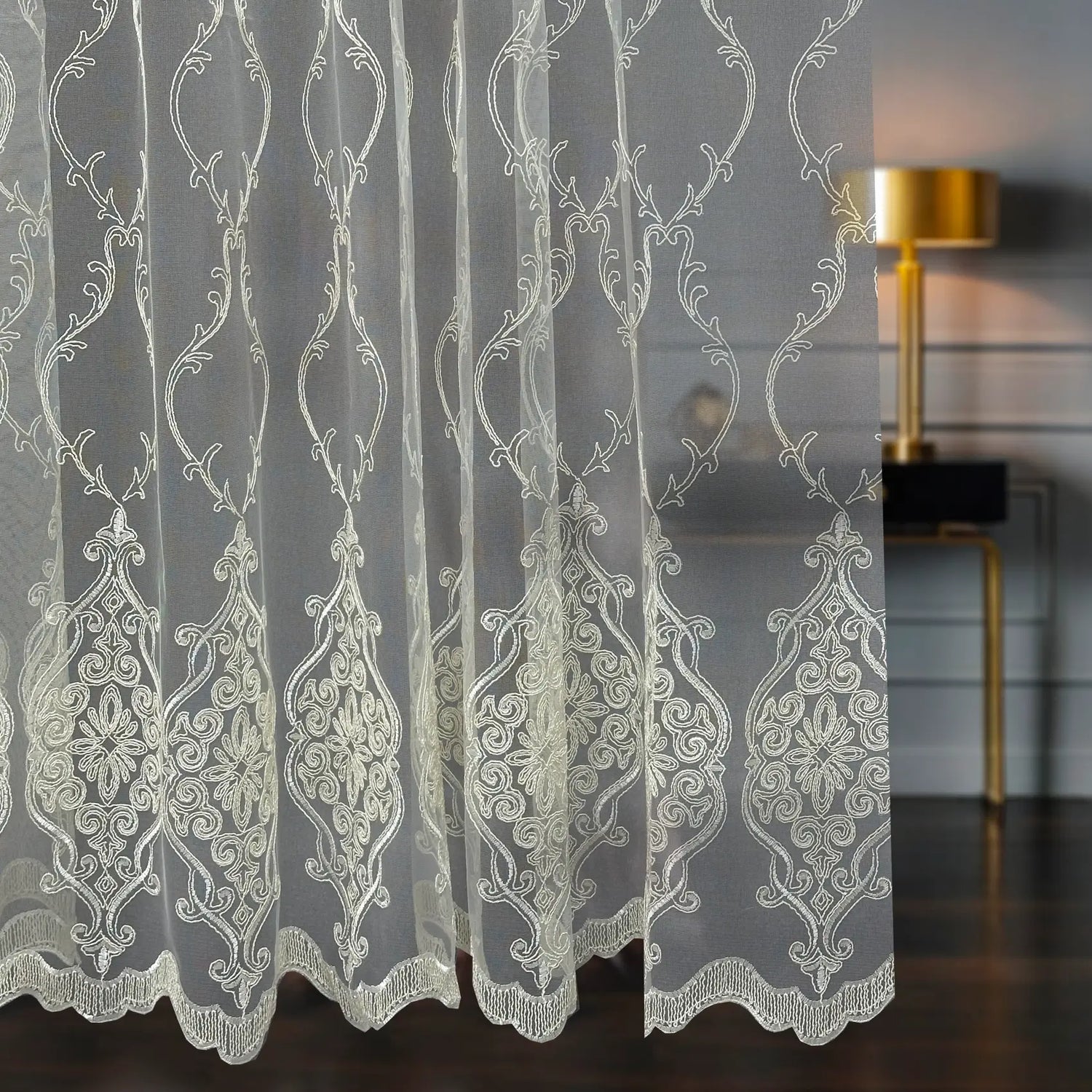 Decorative lace curtain with intricate patterns in a room setting.