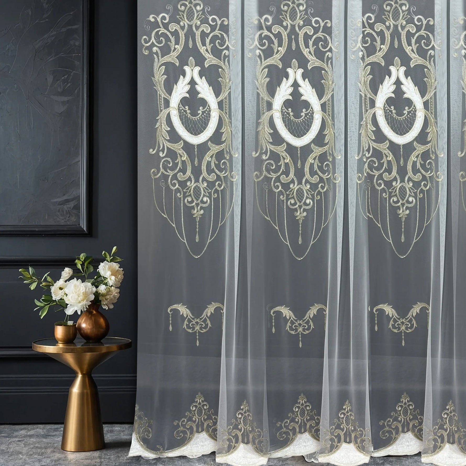 Decorative sheer curtains with gold embroidery in a room setting.