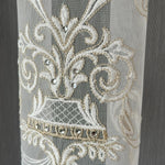 Decorative lace curtains fabric with damask floral patterns and embellishments on a plain background