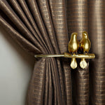Gold bird-shaped curtain tieback on a brown curtain