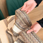 Close-up of a person holding a decorative fabric with intricate patterns on a wooden surface.