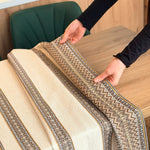 Person unrolling a patterned rug on a wooden floor