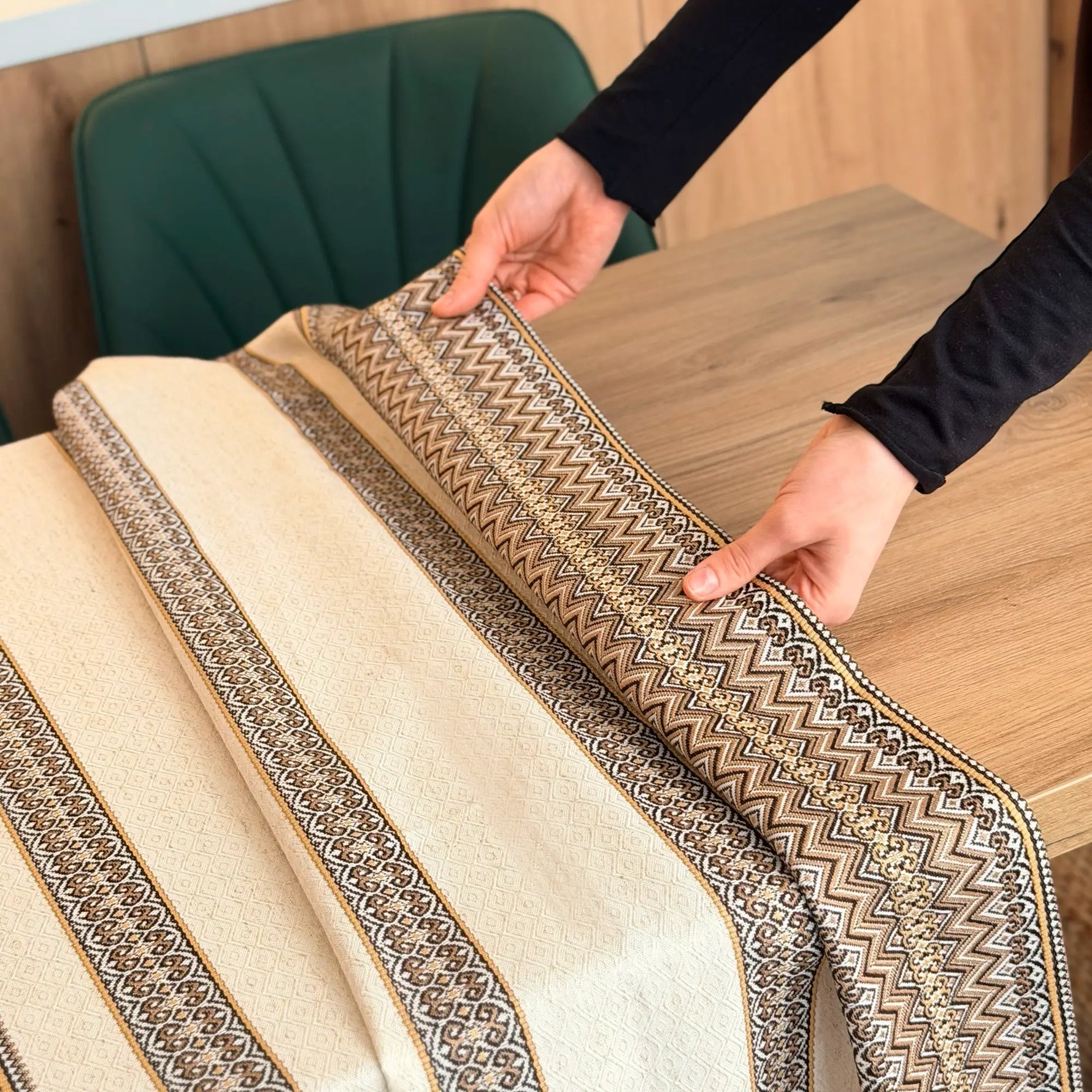 Person unrolling a patterned rug on a wooden floor