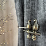 Decorative curtain tieback with bird design on a gray curtain