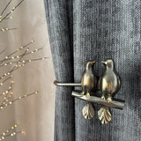 Decorative curtain tieback with bird design on a gray curtain