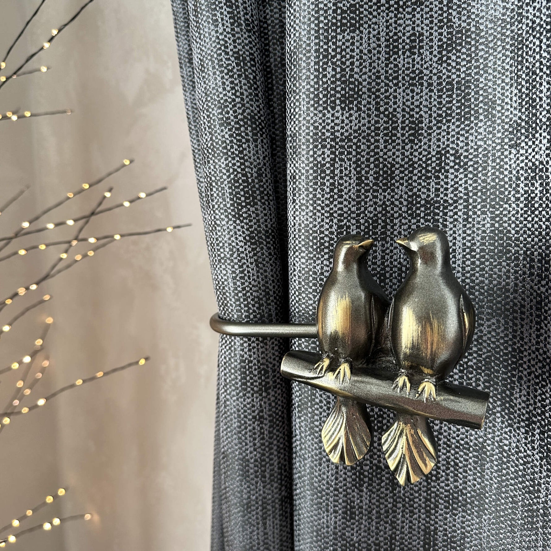 Decorative curtain tieback with bird design on a gray curtain