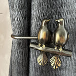 Decorative curtain tieback with two bird sculptures on a textured curtain background