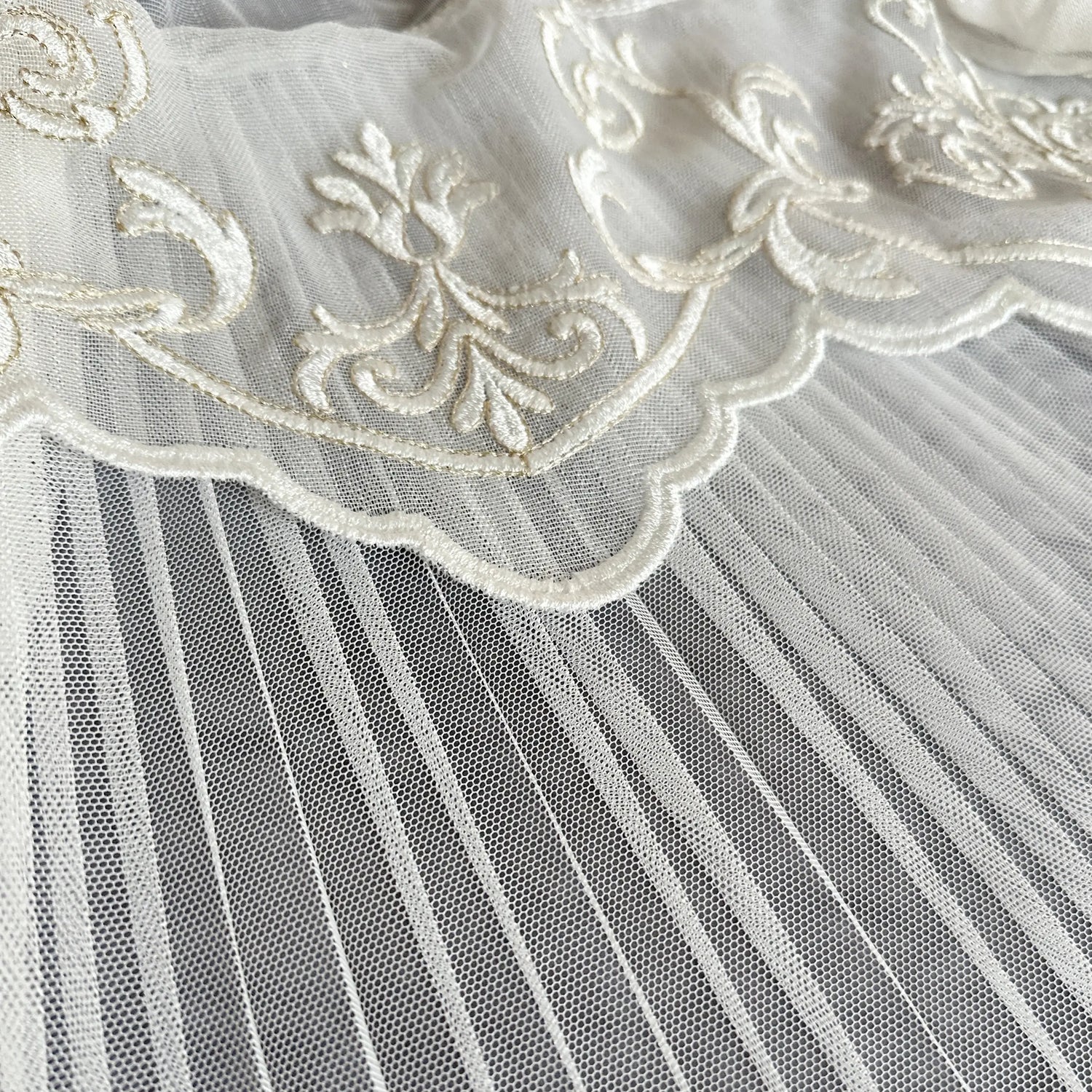Close-up of white tulle fabric with intricate lace detailing