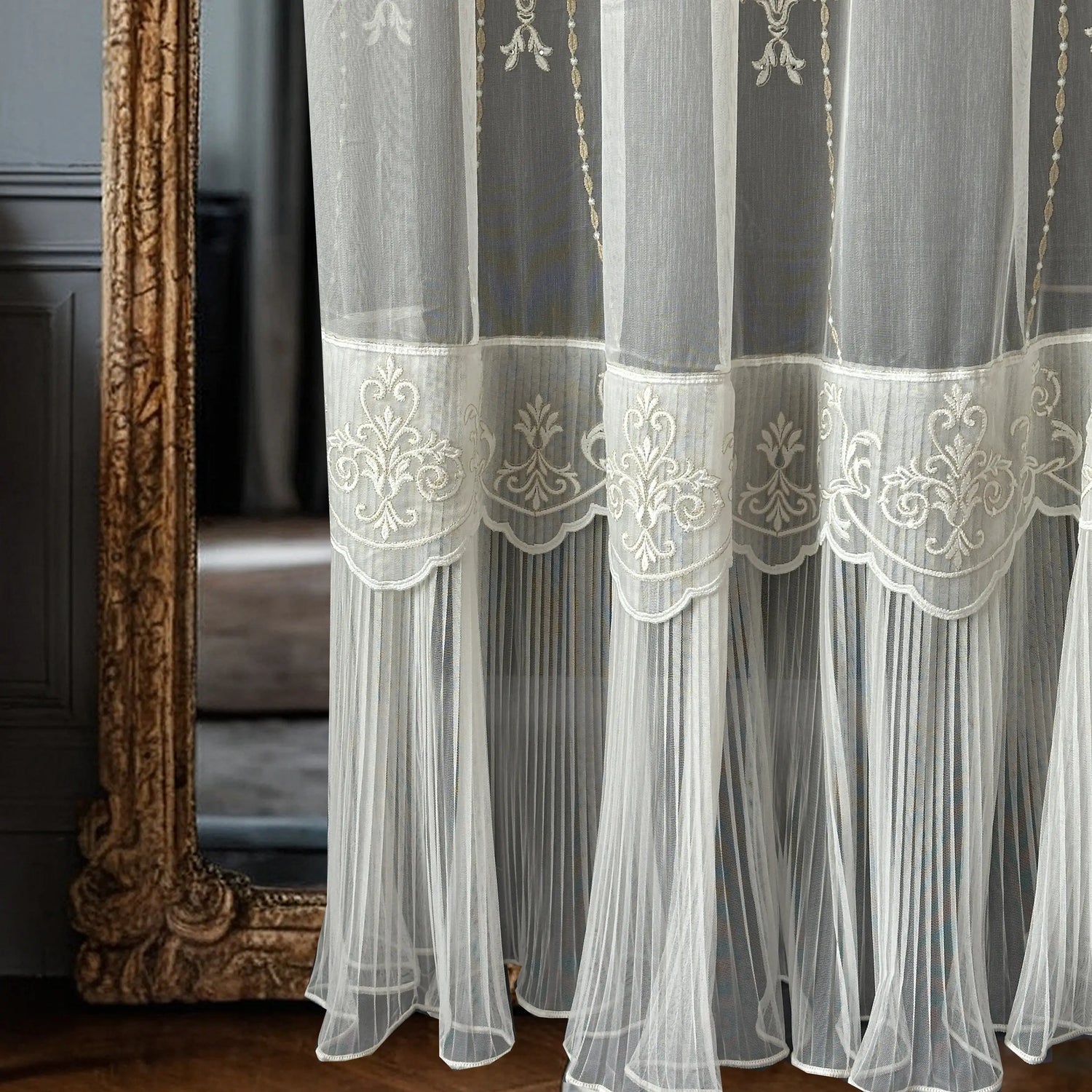 White embroidered curtain with ruffled skirt in front of a decorative mirror