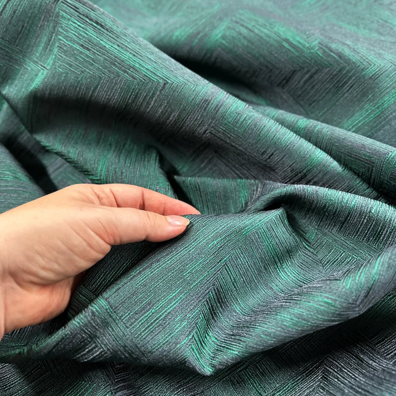 Textured green fabric with a hand touching it