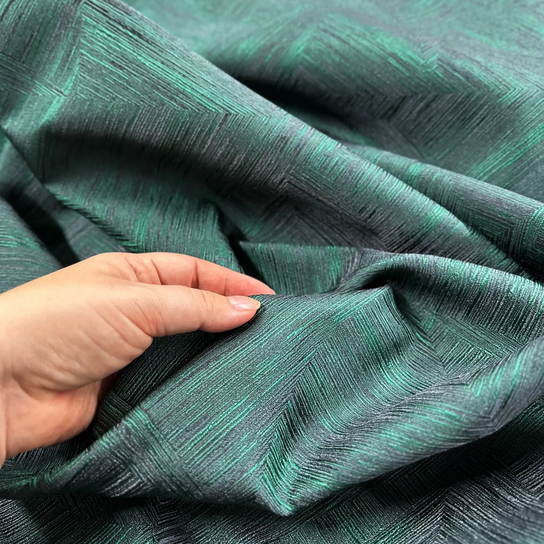 Textured green fabric with a hand touching it
