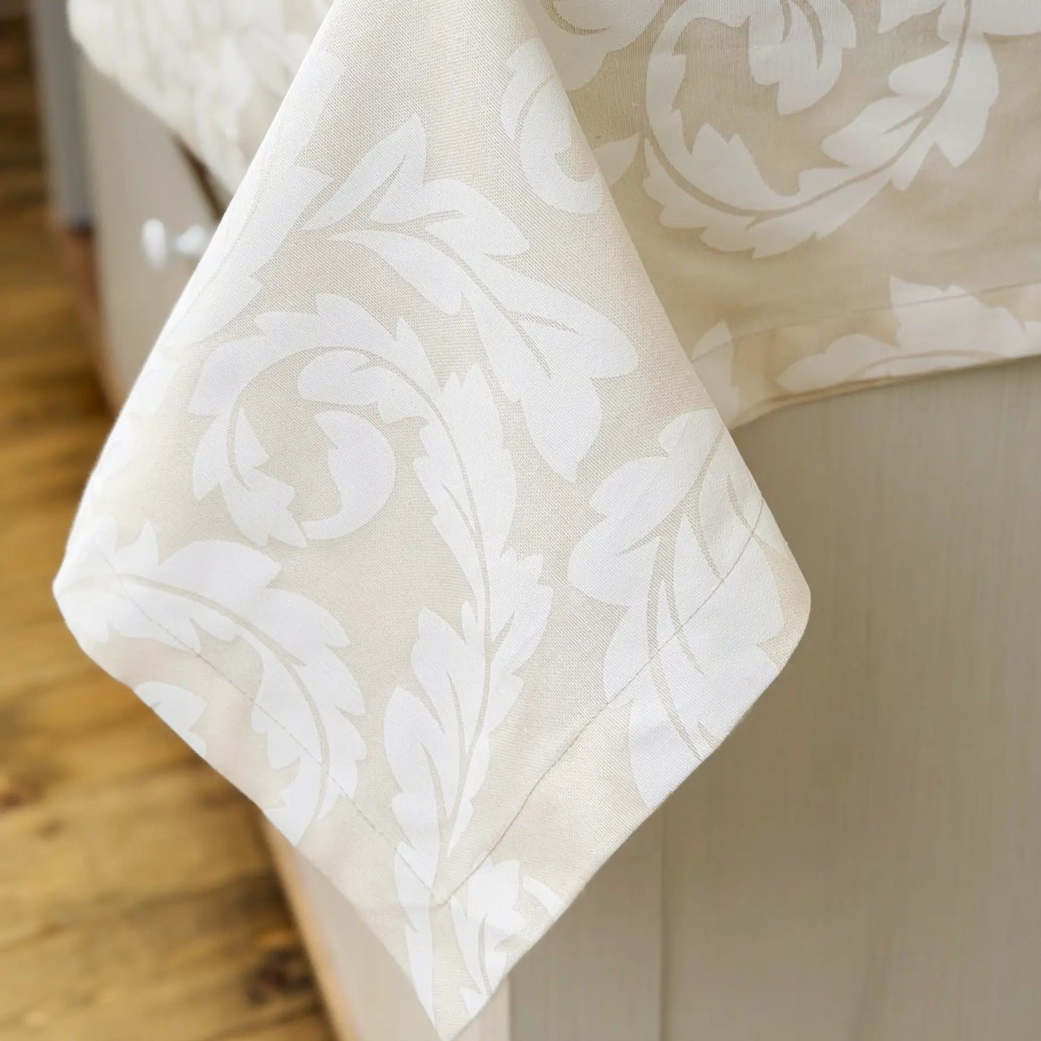 Beige fabric with white floral pattern draped over a surface.
