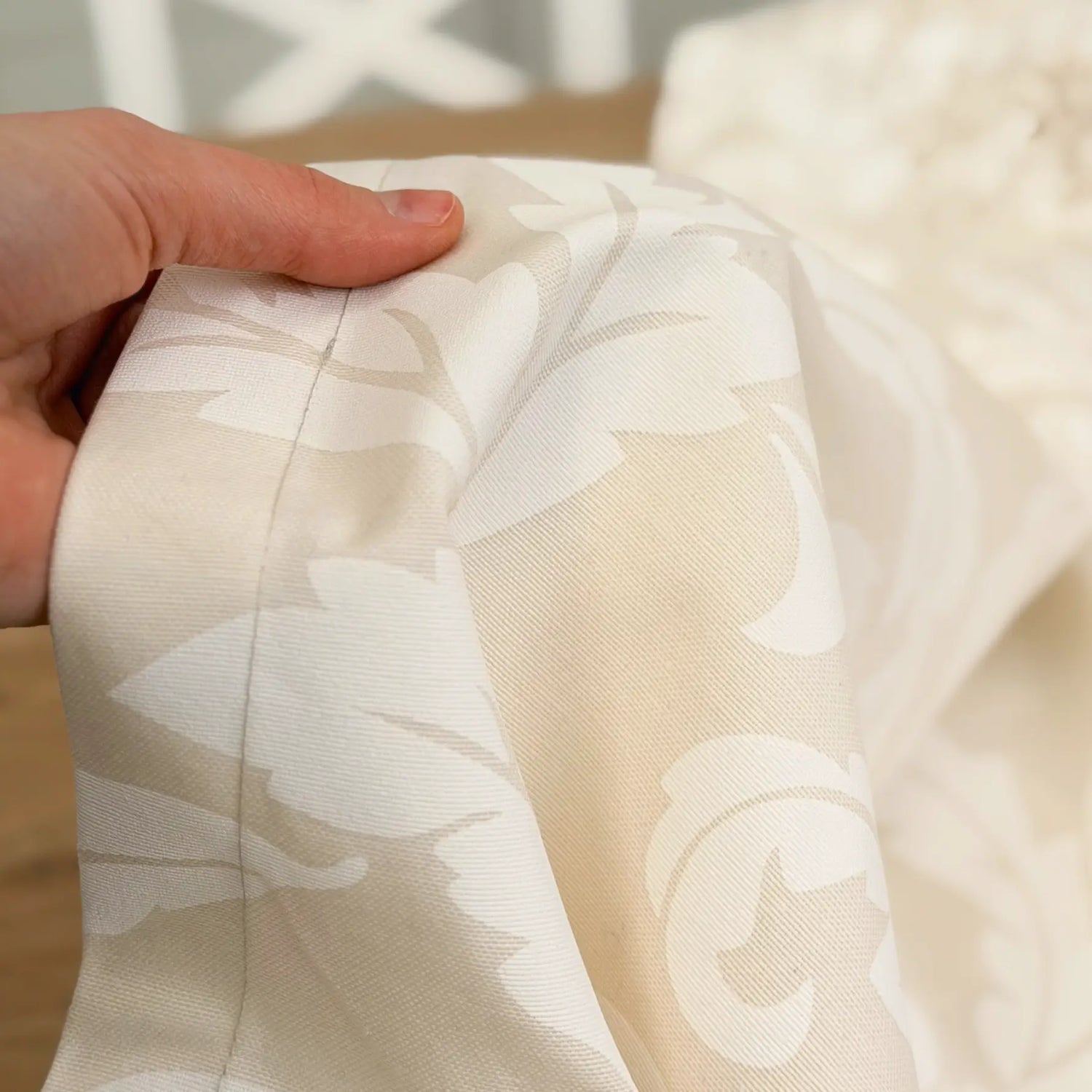 Close-up of a hand holding sheer fabric with floral patterns.