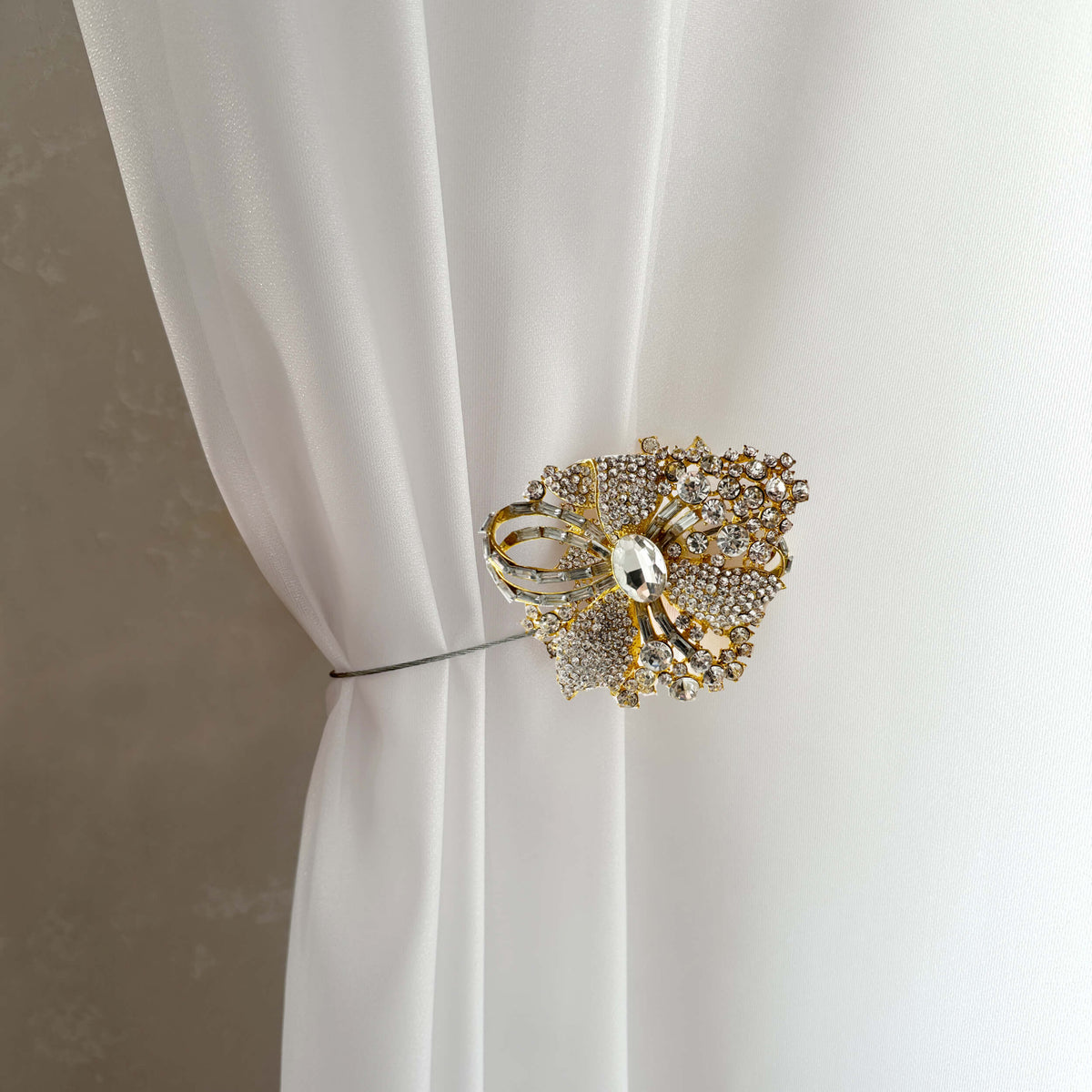 Decorative gold curtain tieback on a white curtain