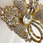 Close-up of a decorative brooch with gold and crystal elements on a light background