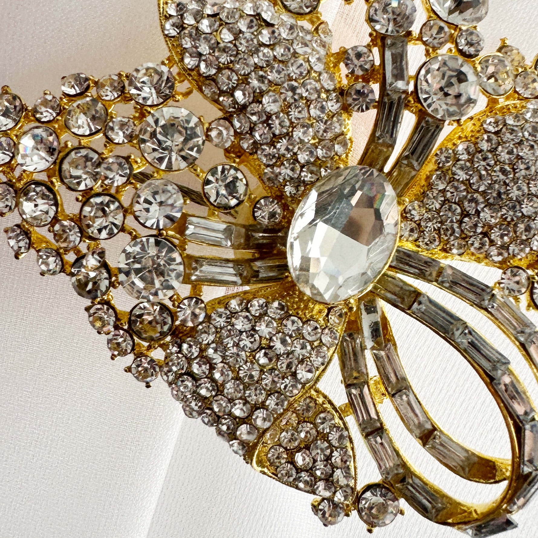 Close-up of a decorative brooch with gold and crystal elements on a light background