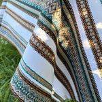 Close-up of a fabric with intricate patterns and colors against a natural background.