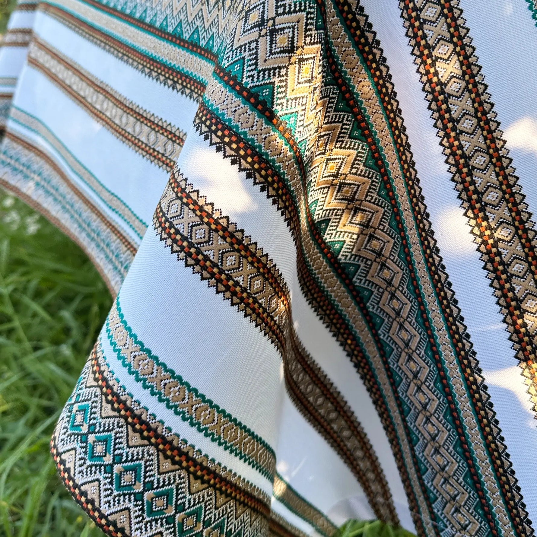Close-up of a fabric with intricate patterns and colors against a natural background.