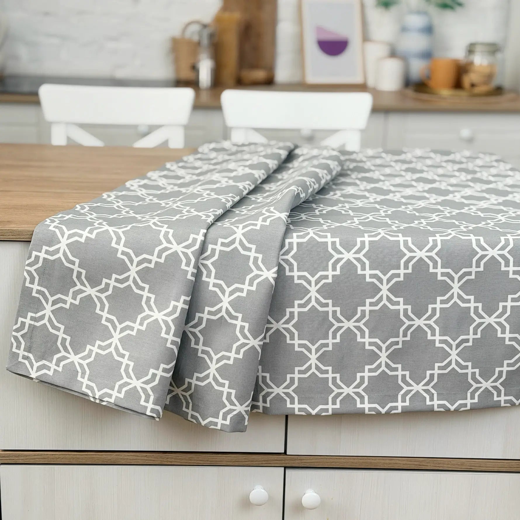 Gray and white patterned tablecloth on a wooden table with a kitchen background