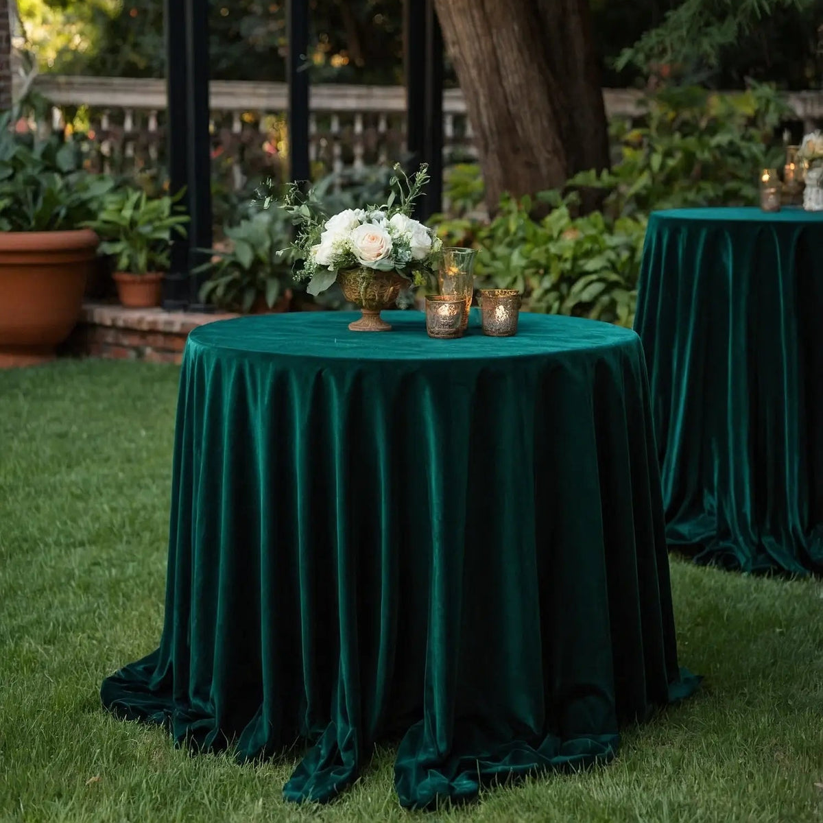 Decorative table with green velvet tablecloth and floral arrangement in an outdoor setting