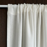 Close-up of a white curtain with a wooden rod on a dark background