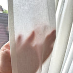 Close-up of a hand holding a sheer white curtain