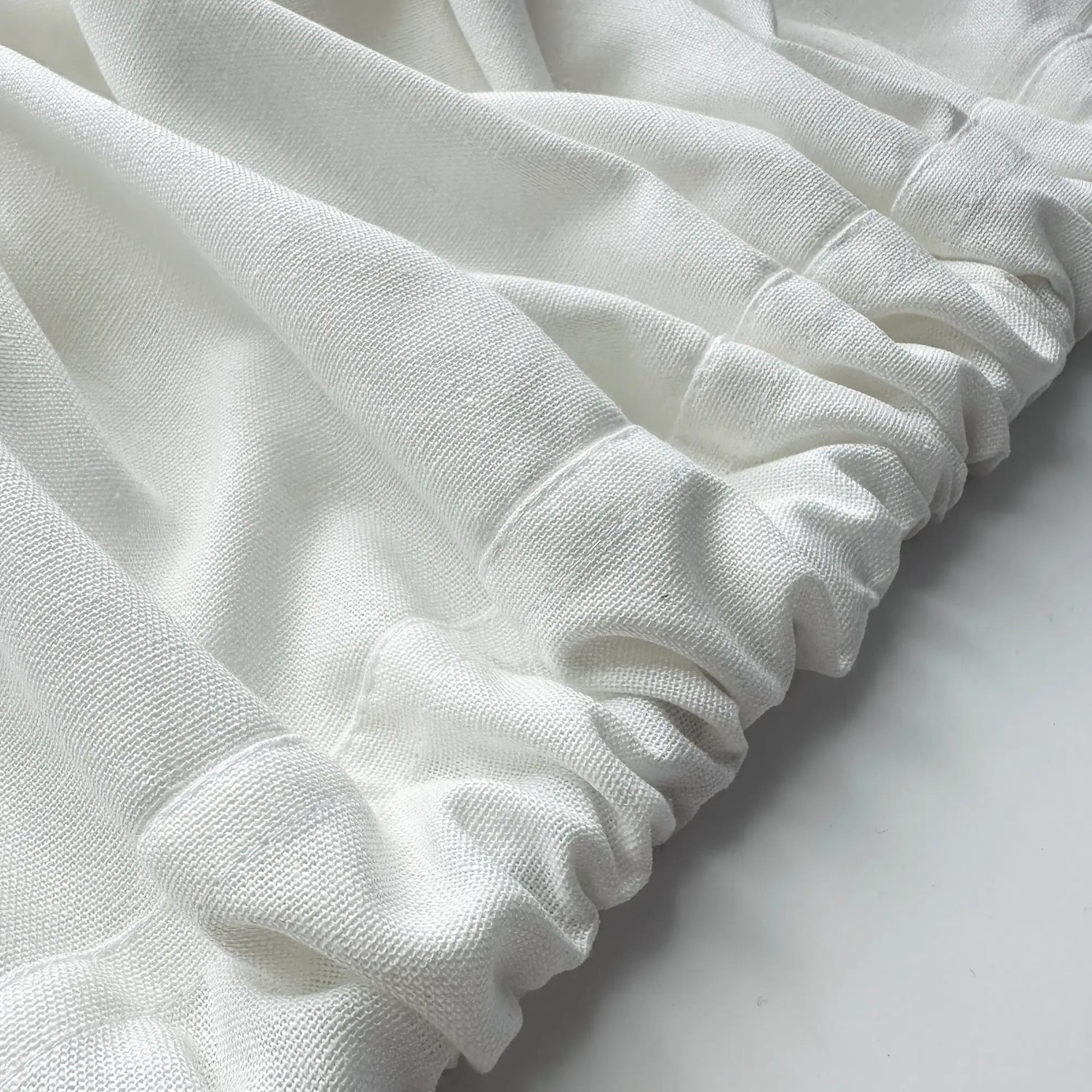 Close-up of white fabric with ruffled edges on a light background