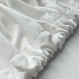 Close-up of white fabric with ruffled edges on a light background