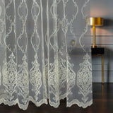 Decorative lace curtain with intricate patterns in a room setting.