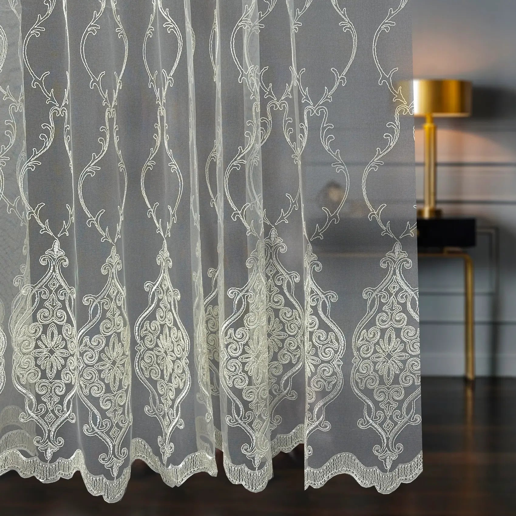 Decorative lace curtain with intricate patterns in a room setting.