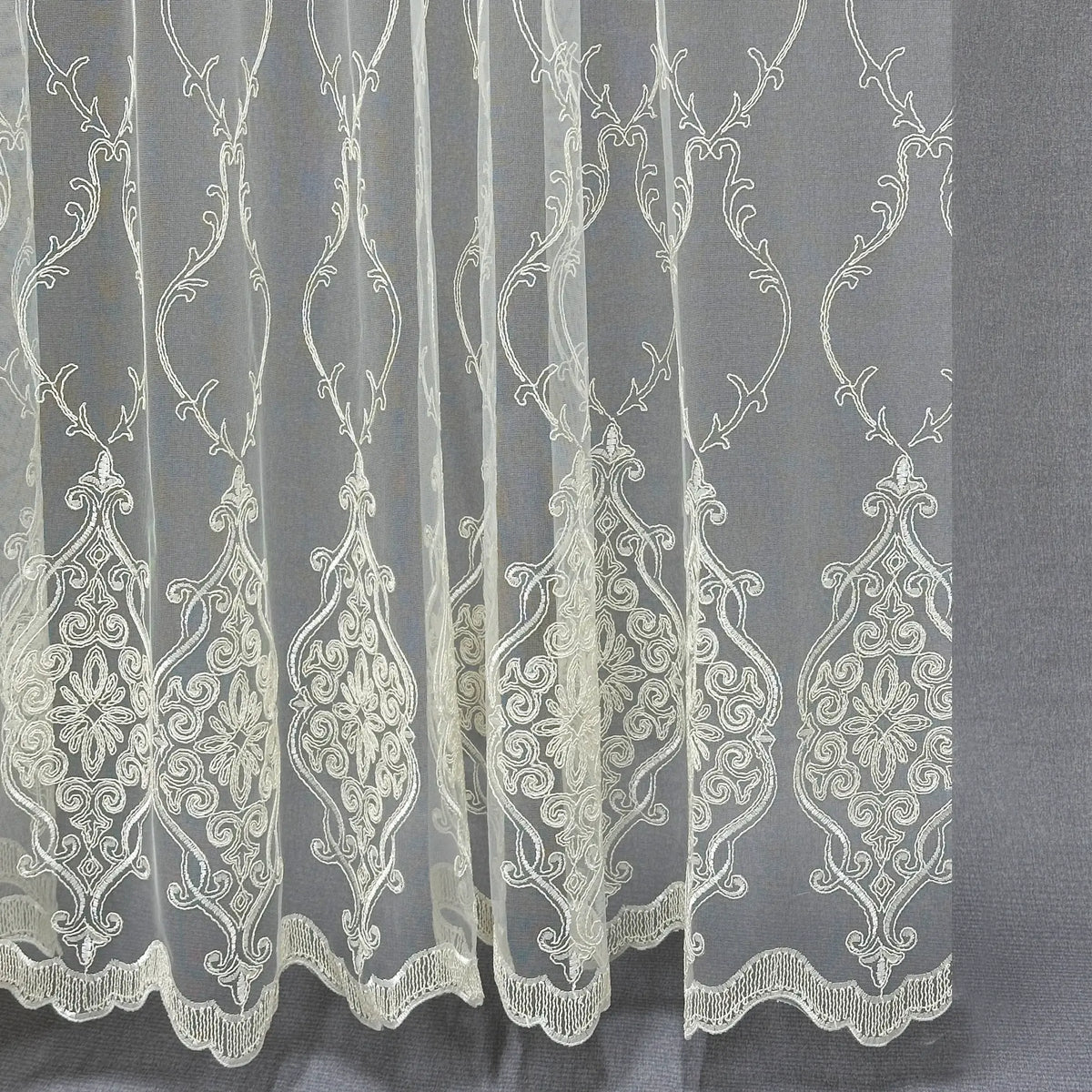Embroidered lace fabric with intricate patterns on a gray background