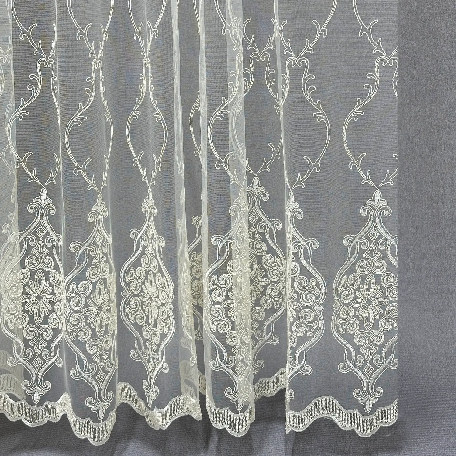 Embroidered lace fabric with intricate patterns on a gray background