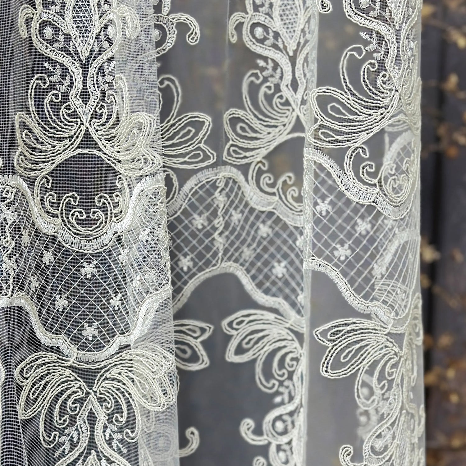 Close-up of intricate lace fabric with white patterns on a dark background