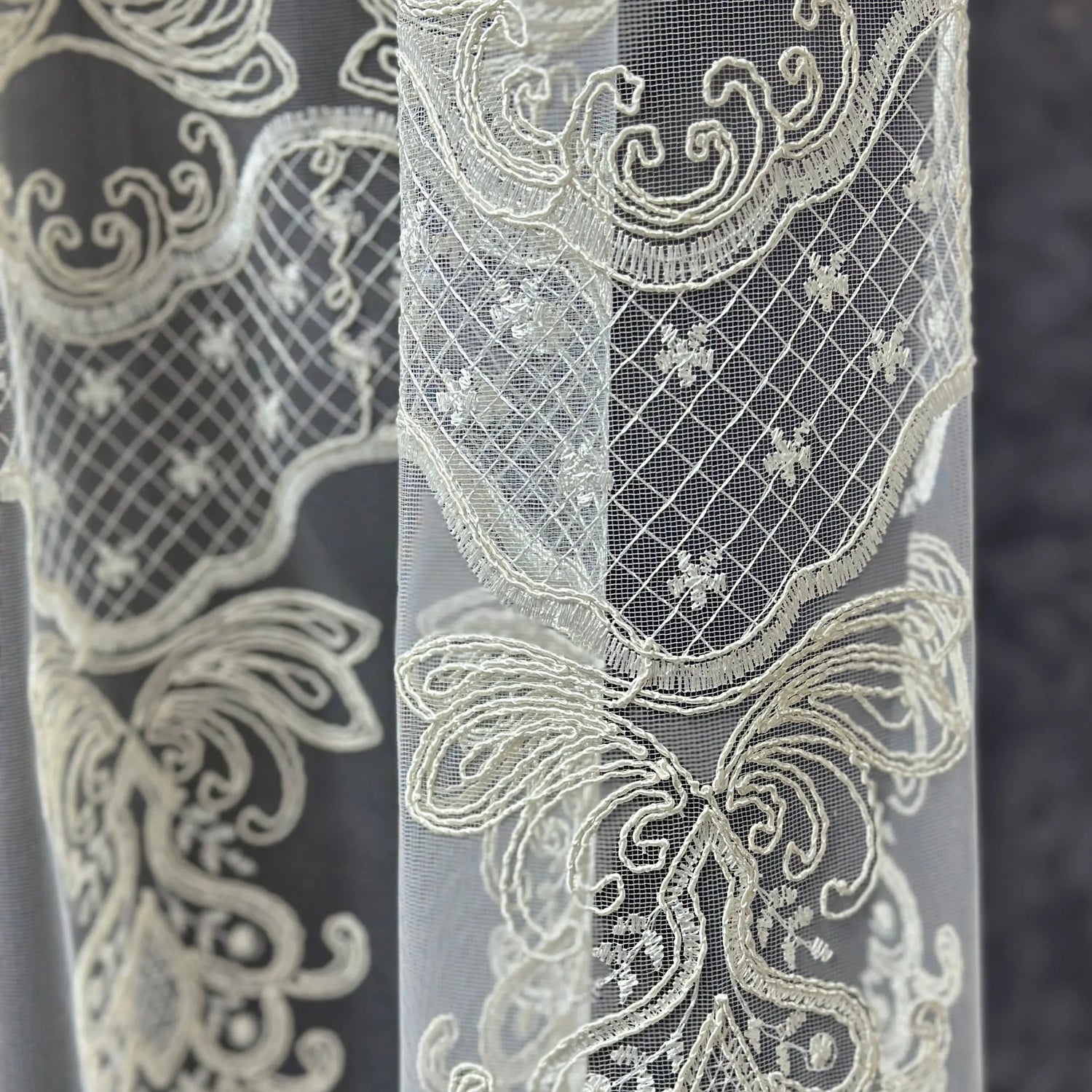 Close-up of intricate lace fabric with detailed patterns on a dark background