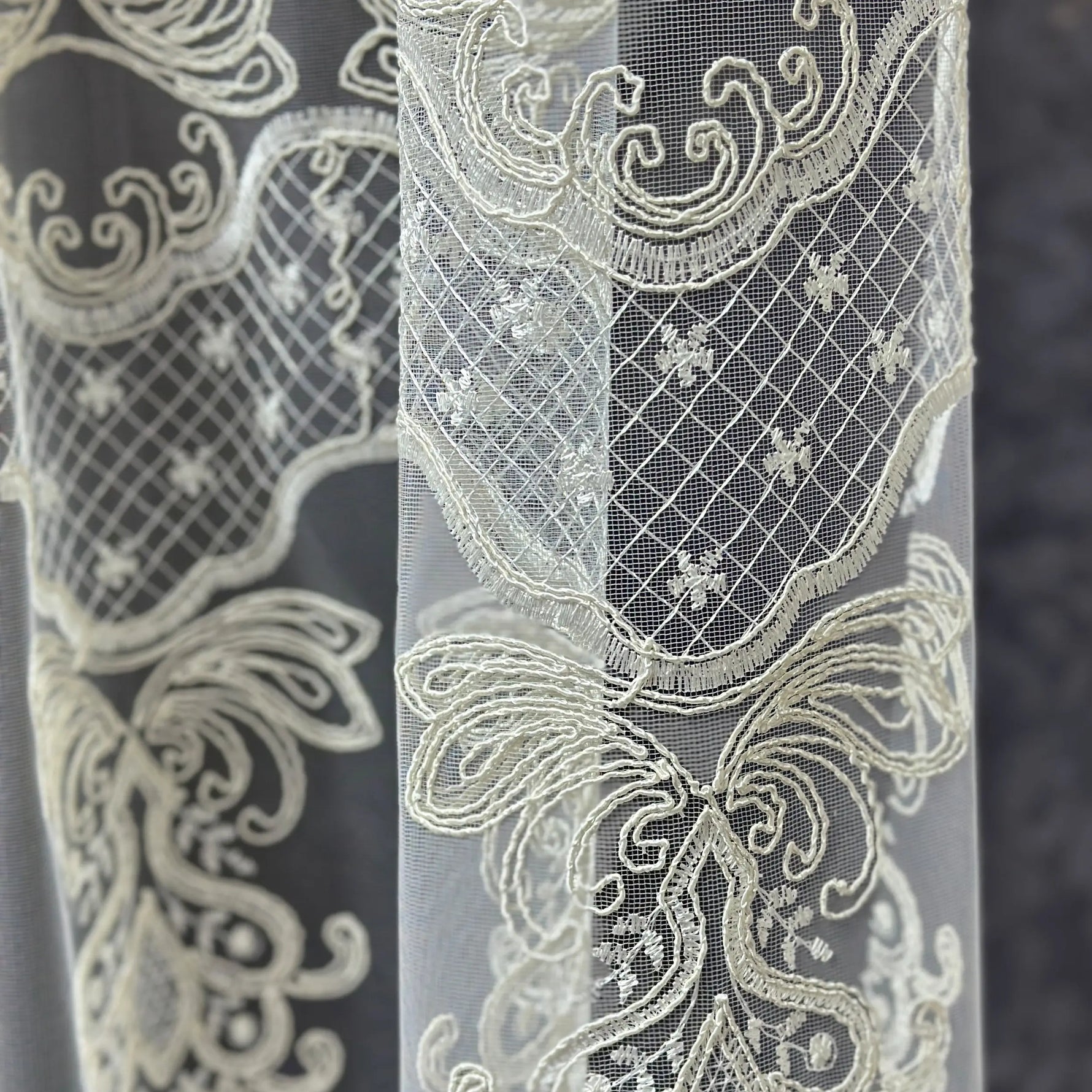 Close-up of intricate lace fabric with detailed patterns on a dark background