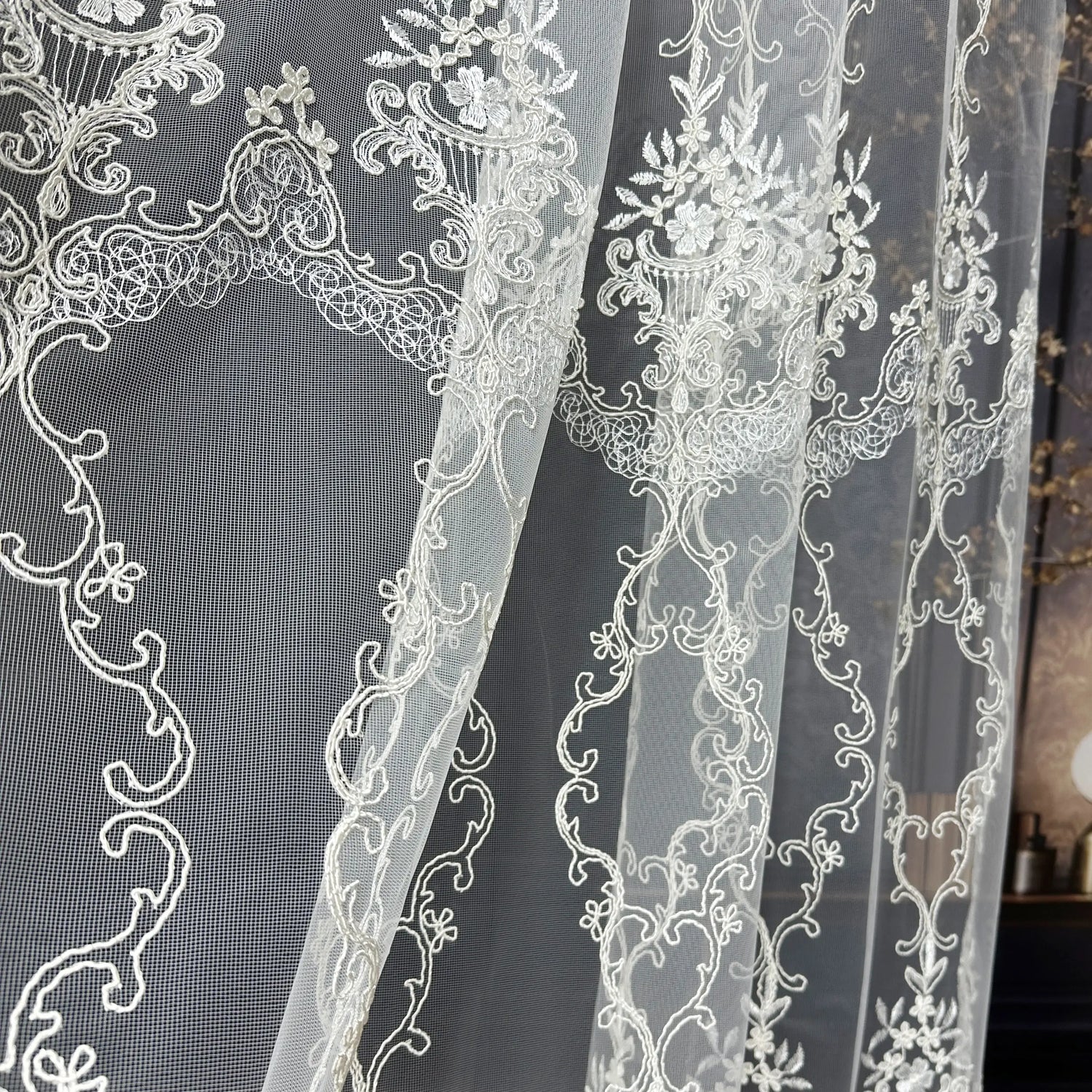 Close-up of white lace fabric with intricate patterns on a dark background