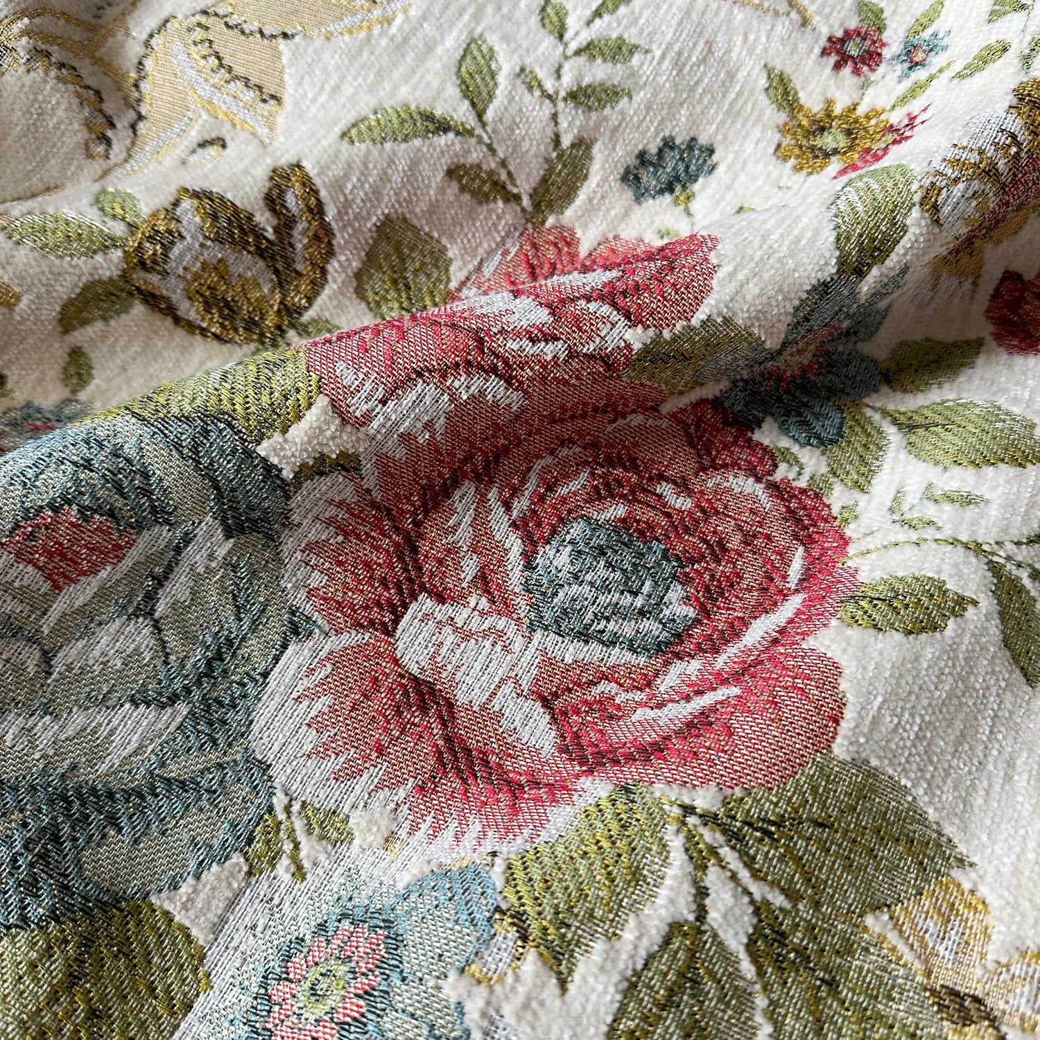 Close-up of floral embroidered fabric with red roses and green leaves.