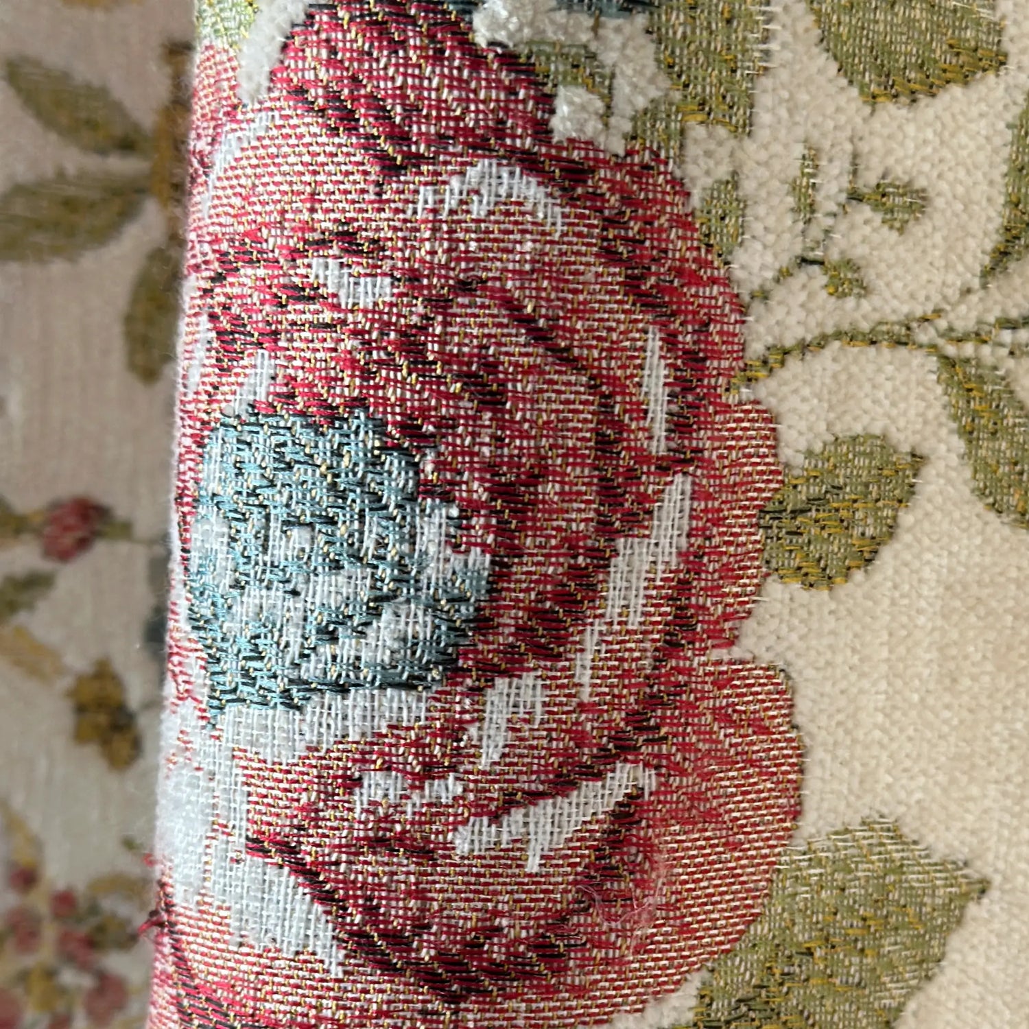 Close-up of a textured fabric with floral patterns and red rose design.