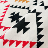 Close-up of fabric with geometric pattern featuring black, red, and orange triangles on a white background.