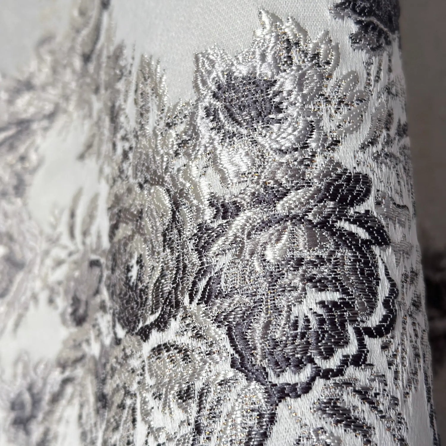Close-up of silver floral lace fabric on a white background