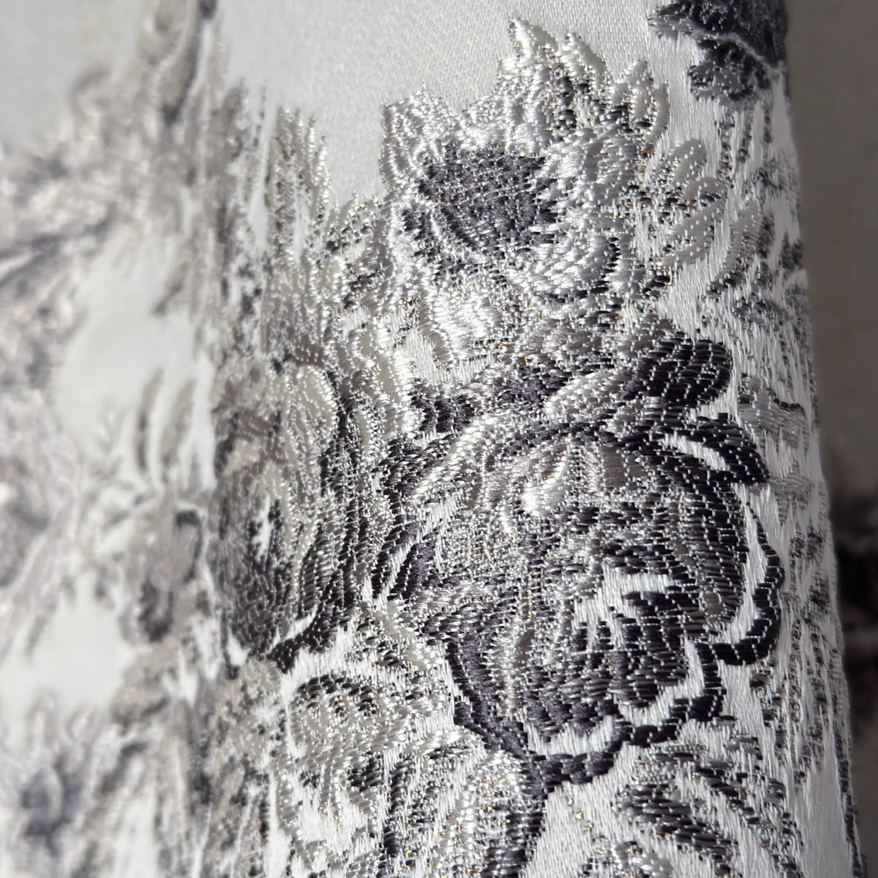 Close-up of silver floral lace fabric on a white background