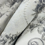Close-up of textured fabric with floral patterns in gray and white.