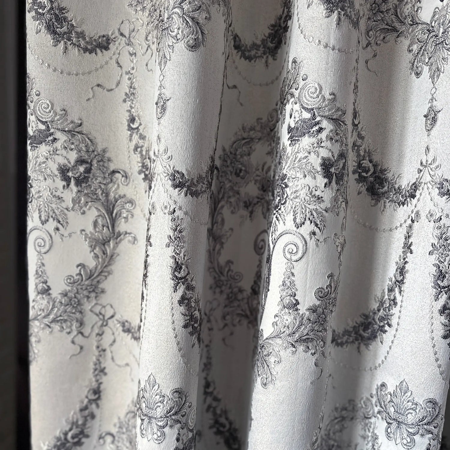 Close-up of decorative fabric with intricate black floral patterns on a white background