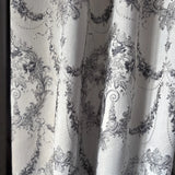 Close-up of decorative fabric with intricate black floral patterns on a white background