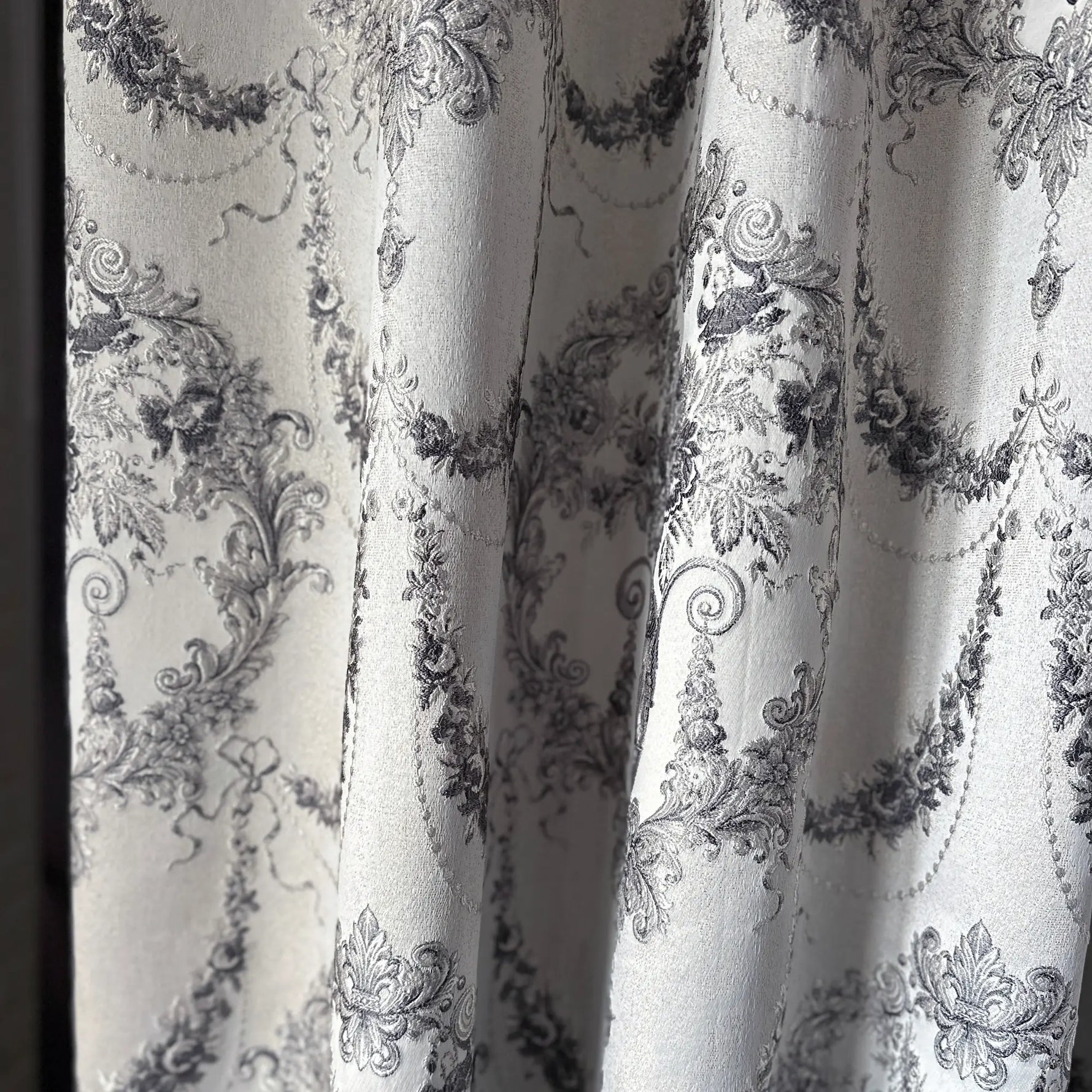 Close-up of decorative fabric with intricate black floral patterns on a white background