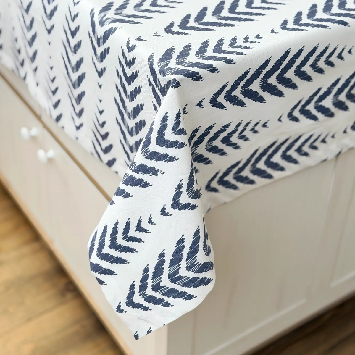 Navy leaf patterned comforter on a bed with white bedding