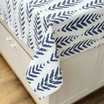 Navy leaf patterned comforter on a bed with white bedding