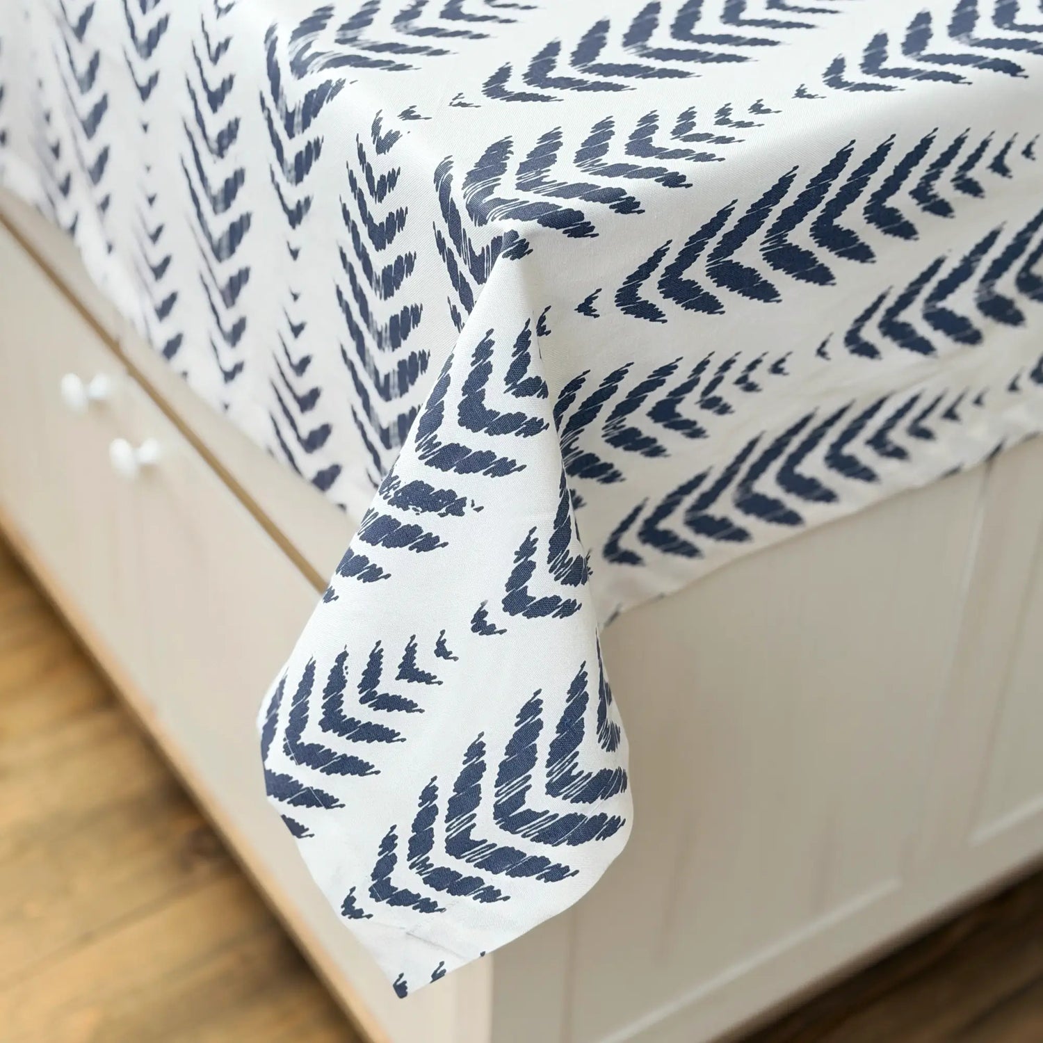 Navy leaf patterned comforter on a bed with white bedding