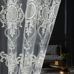 White lace curtain with intricate patterns in a room setting