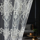White lace curtain with intricate patterns in a room setting